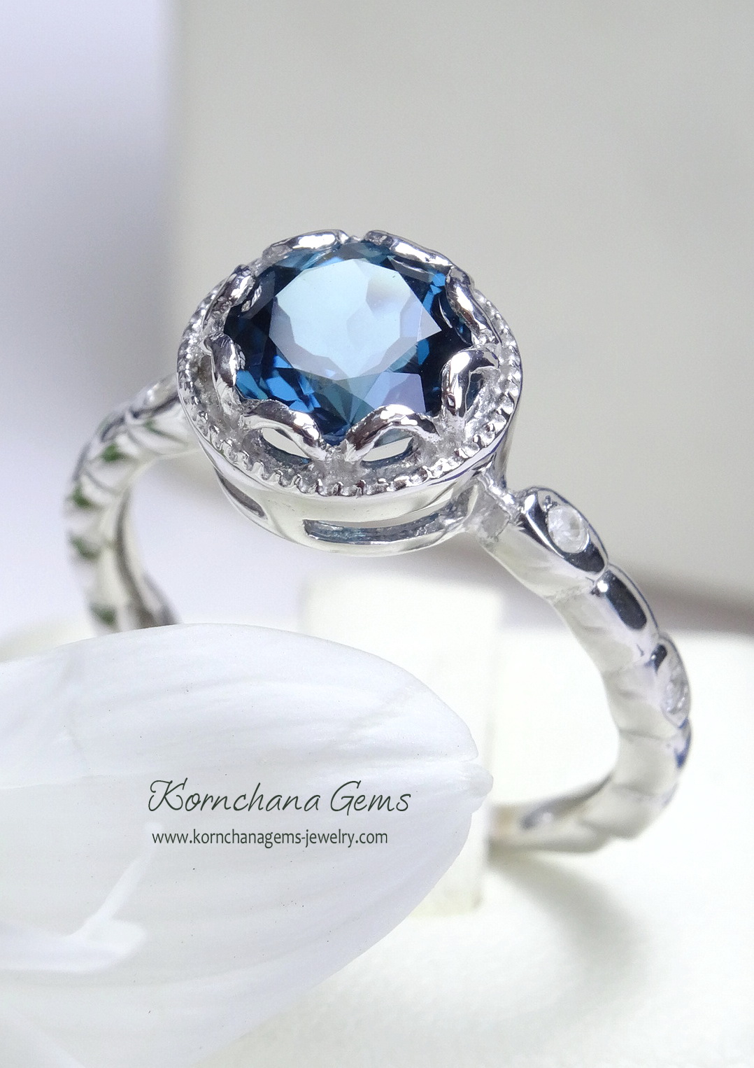 แหวนลอนดอนบลูโทพาส แหวนพลอยสีน้ำเงินสวยทรงกลม ตัวเรือนแหวนบิดเป็นเกลียว สวยเก๋ ลักษณะการฝังเป็นแบบ Bezel เป็นการฝังแบบหุ้ม