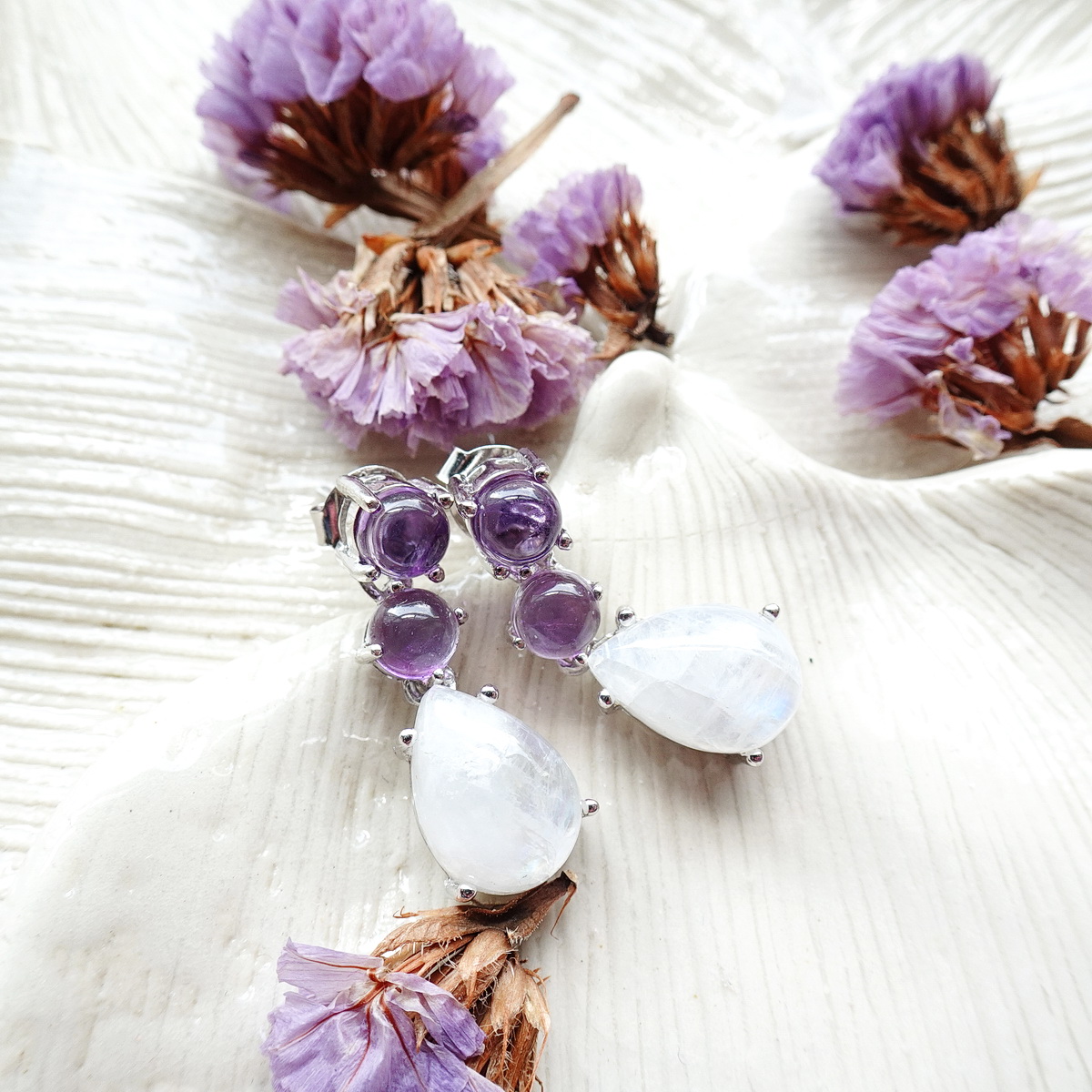 ต่างหูห้อยเรนโบว์มูนสโตน หรือมุกดาหารทรงลูกแพรหรือหยดน้ำ อัญมณีประจำราศีเมถุน ให้สีสะท้อนแสงเหลือบรุ้ง ด้านบนฝังอเมทิสท์สีม่วง ตัดกับสีขาวรุ้งของมูนสโตน สวยงามมากค่ะ