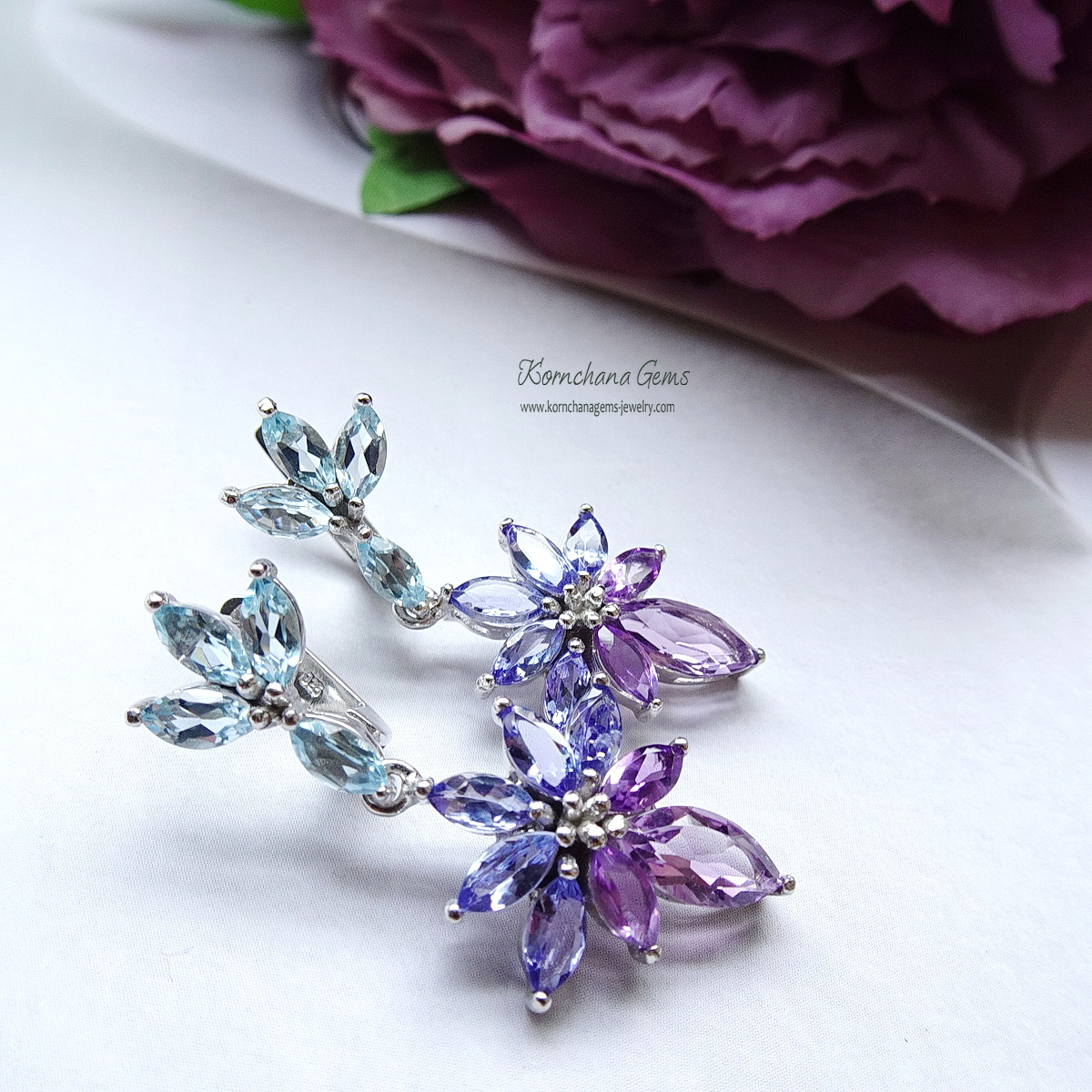 ต่างหูพลอยระย้าเฉดม่วงฟ้า เก๋ด้วยพลอยทรงมาคีทุกเม็ด ตัวเรือนฝังพลอยบลูโทพาสสีฟ้าใส ห้อยด้วยแทนซาไนท์สีม่วงอมฟ้าครามไล่เฉดไปม่วงอมชมพูอเมทิสท์ สวยหวานละมุน